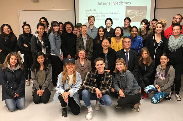 SF State group of students posing in front of a projector screen