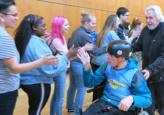 group of people lined up giving a high five to a person in a wheel chair