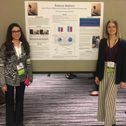 two women standing in front of a poster presentation