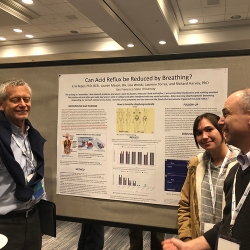 three people standing in front of a poster presentation