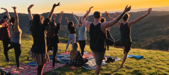 People on hill at sunset doing yoga